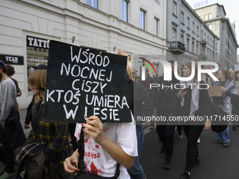 A demonstrator holds a sign that reads ''Amongst night's silence someone is dying in the woods'' as she rallies against the Polish Prime Min...