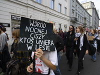 A demonstrator holds a sign that reads ''Amongst night's silence someone is dying in the woods'' as she rallies against the Polish Prime Min...