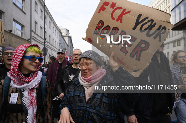 A demonstrator holds a sign that reads ''Fuck your border'' as she rallies against the Polish Prime Minister Donald Tusk's decision to suspe...