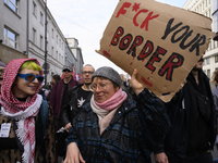 A demonstrator holds a sign that reads ''Fuck your border'' as she rallies against the Polish Prime Minister Donald Tusk's decision to suspe...