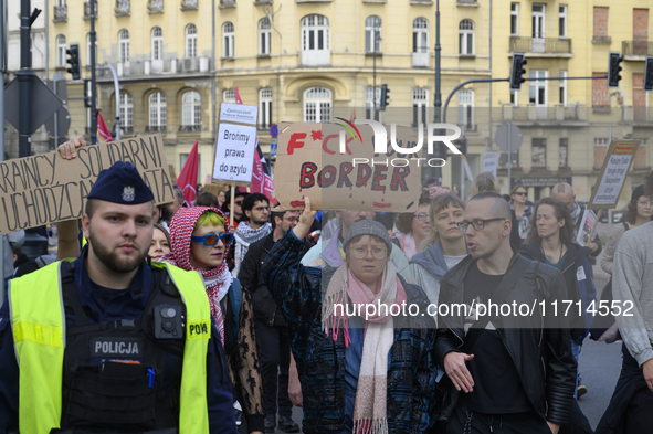 A demonstrator holds a sign that reads ''Fuck your border'' as she rallies against the Polish Prime Minister Donald Tusk's decision to suspe...