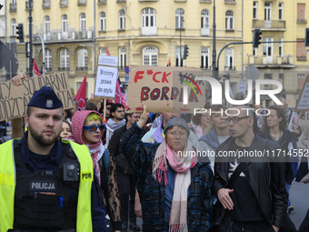 A demonstrator holds a sign that reads ''Fuck your border'' as she rallies against the Polish Prime Minister Donald Tusk's decision to suspe...