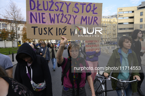 A demonstrator holds a sign that reads ''A longer table, not a higher wall. Tusk fuck off'' as she rallies against the Polish Prime Minister...