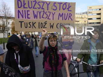 A demonstrator holds a sign that reads ''A longer table, not a higher wall. Tusk fuck off'' as she rallies against the Polish Prime Minister...