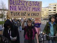 A demonstrator holds a sign that reads ''A longer table, not a higher wall. Tusk fuck off'' as she rallies against the Polish Prime Minister...