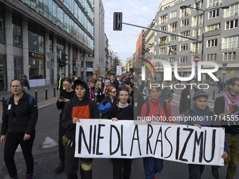 People hold a banner that reads ''No to racism'' as they rally against the Polish Prime Minister Donald Tusk's decision to suspend the right...