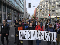 People hold a banner that reads ''No to racism'' as they rally against the Polish Prime Minister Donald Tusk's decision to suspend the right...