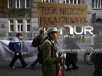 People hold signs that read ''Tusk destroys human rights'' as they rally against the Polish Prime Minister Donald Tusk's decision to suspend...