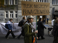 People hold signs that read ''Tusk destroys human rights'' as they rally against the Polish Prime Minister Donald Tusk's decision to suspend...