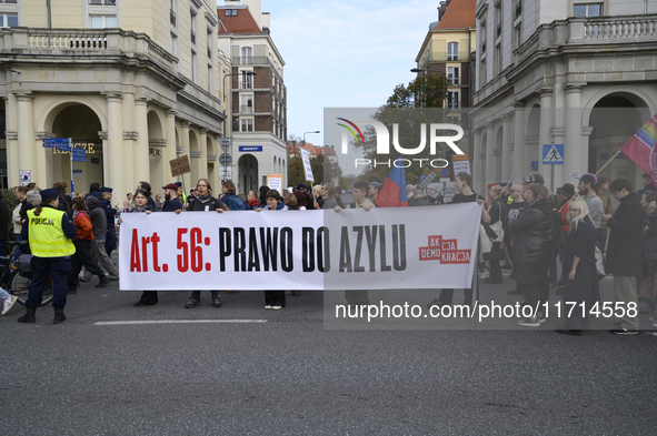 People carry a banner that reads ''Article 56: Right to asylum'' as they rally against the Polish Prime Minister Donald Tusk's decision to s...