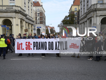 People carry a banner that reads ''Article 56: Right to asylum'' as they rally against the Polish Prime Minister Donald Tusk's decision to s...