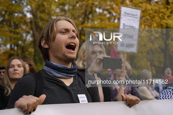 People hold signs and shout slogans as they rally against the Polish Prime Minister Donald Tusk's decision to suspend the right to asylum wi...