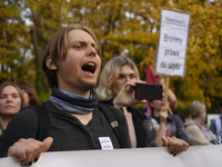 People hold signs and shout slogans as they rally against the Polish Prime Minister Donald Tusk's decision to suspend the right to asylum wi...