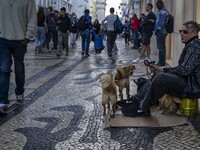 A person with several dogs begs for money on a street in the Baixa district in Lisbon, Portugal, on October 27, 2024. (