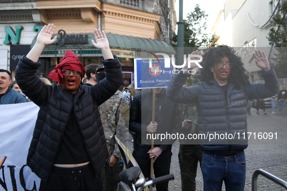 Participants of the counter-demonstration organized by the All-Polish Youth dress as refugees in blackface, and Polish soldiers point rifles...