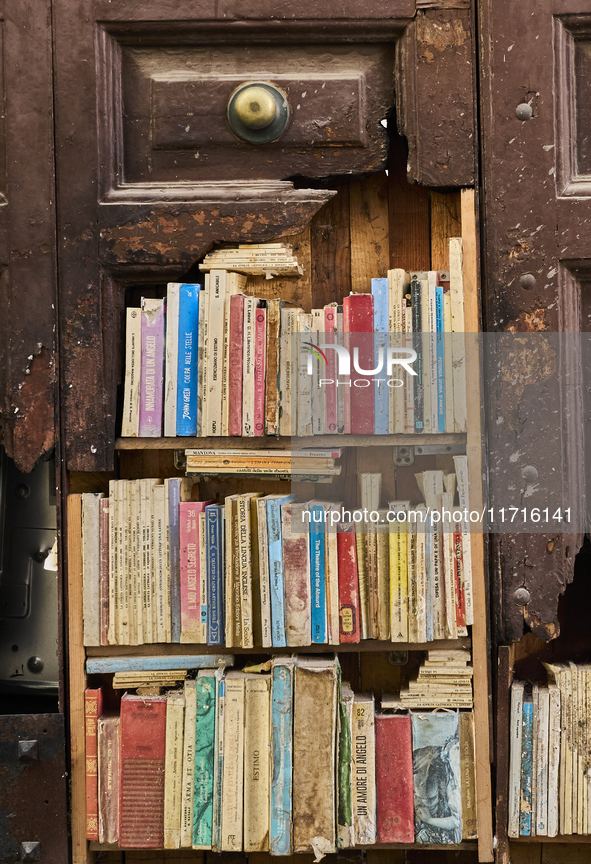 A unique artistic setup in Lucera, Italy, on October 3, 2024, features old, weathered books arranged on shelves built into a broken section...