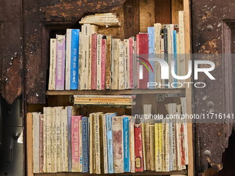 A unique artistic setup in Lucera, Italy, on October 3, 2024, features old, weathered books arranged on shelves built into a broken section...