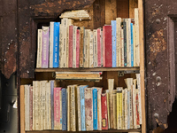 A unique artistic setup in Lucera, Italy, on October 3, 2024, features old, weathered books arranged on shelves built into a broken section...