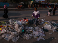 A municipal worker sweeps a street littered with discarded plastic bags, which are burned after collection, contributing to air pollution in...