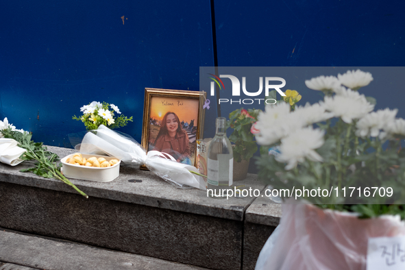 A memorial tribute for a victim of the Itaewon tragedy includes flowers, a framed photo, snacks, and drinks, placed in remembrance in the It...