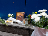 A memorial tribute for a victim of the Itaewon tragedy includes flowers, a framed photo, snacks, and drinks, placed in remembrance in the It...