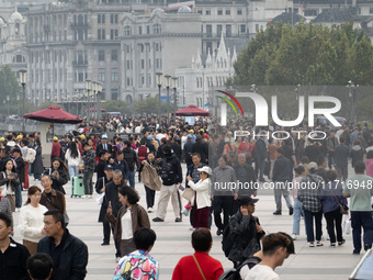 Tourists tour on a waterfront landscape platform along the Bund in Shanghai, China, on October 28, 2024. (