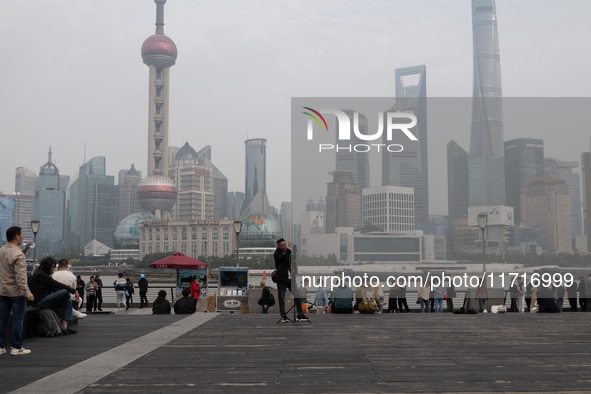 An anchor broadcasts a live webcast with the Lujiazui business district as the background on the Bund landscape platform in Shanghai, China,...