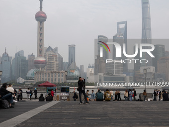 An anchor broadcasts a live webcast with the Lujiazui business district as the background on the Bund landscape platform in Shanghai, China,...