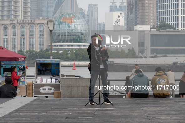 An anchor broadcasts a live webcast with the Lujiazui business district as the background on the Bund landscape platform in Shanghai, China,...