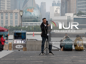 An anchor broadcasts a live webcast with the Lujiazui business district as the background on the Bund landscape platform in Shanghai, China,...