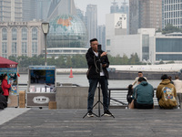 An anchor broadcasts a live webcast with the Lujiazui business district as the background on the Bund landscape platform in Shanghai, China,...