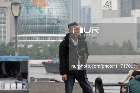 An anchor broadcasts a live webcast with the Lujiazui business district as the background on the Bund landscape platform in Shanghai, China,...