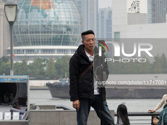 An anchor broadcasts a live webcast with the Lujiazui business district as the background on the Bund landscape platform in Shanghai, China,...