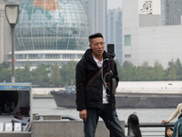 An anchor broadcasts a live webcast with the Lujiazui business district as the background on the Bund landscape platform in Shanghai, China,...