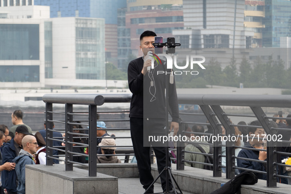 An anchor broadcasts a live webcast with the Lujiazui business district as the background on the Bund landscape platform in Shanghai, China,...