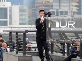 An anchor broadcasts a live webcast with the Lujiazui business district as the background on the Bund landscape platform in Shanghai, China,...