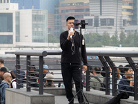 An anchor broadcasts a live webcast with the Lujiazui business district as the background on the Bund landscape platform in Shanghai, China,...