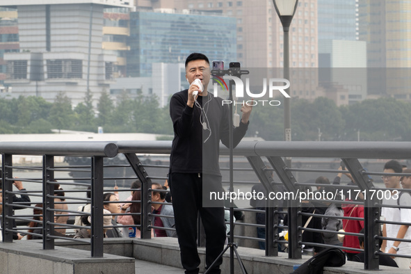 An anchor broadcasts a live webcast with the Lujiazui business district as the background on the Bund landscape platform in Shanghai, China,...