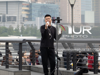 An anchor broadcasts a live webcast with the Lujiazui business district as the background on the Bund landscape platform in Shanghai, China,...