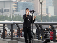 An anchor broadcasts a live webcast with the Lujiazui business district as the background on the Bund landscape platform in Shanghai, China,...