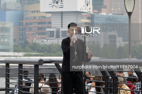 An anchor broadcasts a live webcast with the Lujiazui business district as the background on the Bund landscape platform in Shanghai, China,...