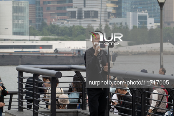 An anchor broadcasts a live webcast with the Lujiazui business district as the background on the Bund landscape platform in Shanghai, China,...