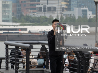 An anchor broadcasts a live webcast with the Lujiazui business district as the background on the Bund landscape platform in Shanghai, China,...