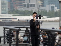 An anchor broadcasts a live webcast with the Lujiazui business district as the background on the Bund landscape platform in Shanghai, China,...