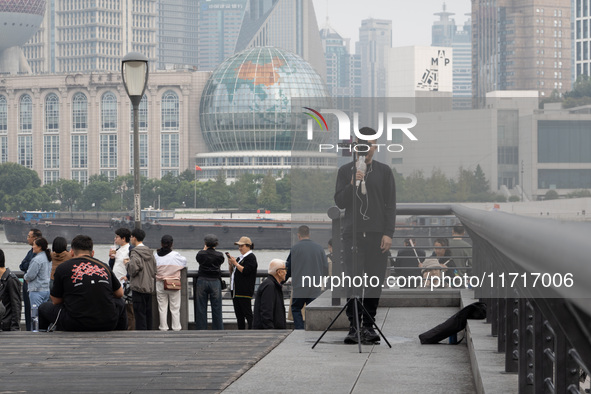 An anchor broadcasts a live webcast with the Lujiazui business district as the background on the Bund landscape platform in Shanghai, China,...