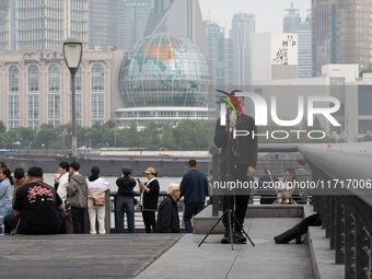 An anchor broadcasts a live webcast with the Lujiazui business district as the background on the Bund landscape platform in Shanghai, China,...