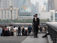 An anchor broadcasts a live webcast with the Lujiazui business district as the background on the Bund landscape platform in Shanghai, China,...