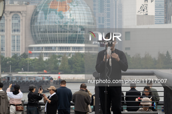 An anchor broadcasts a live webcast with the Lujiazui business district as the background on the Bund landscape platform in Shanghai, China,...