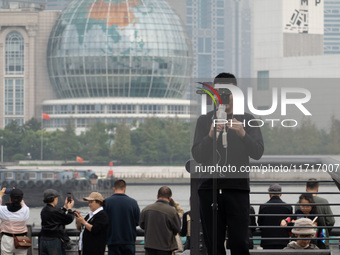 An anchor broadcasts a live webcast with the Lujiazui business district as the background on the Bund landscape platform in Shanghai, China,...