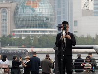 An anchor broadcasts a live webcast with the Lujiazui business district as the background on the Bund landscape platform in Shanghai, China,...